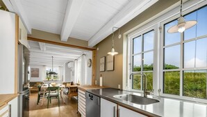 Une cuisine moderne dotée d’une grande fenêtre, d’un plancher en bois et d’un coin repas avec une table et des chaises.