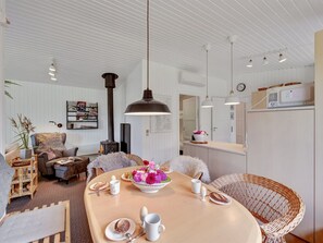 Ein gemütliches Wohnzimmer mit einem runden Tisch, einer Couch und einem Kamin. Ein Essbereich mit einem Büfett und einer sichtbaren Küche im Hintergrund.