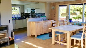 A modern kitchen with wooden cabinets, a central island, and a dining area with a table and chairs. - "Gudrid" - 500m from the sea by Interhome (Fanø)