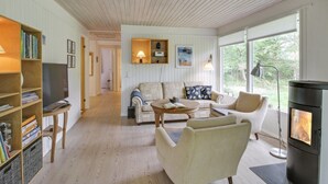 A cozy living room with a fireplace, wooden bookshelves, a sofa, and a coffee table. - "Chrissie" - 150m from the sea by Interhome (Hals)