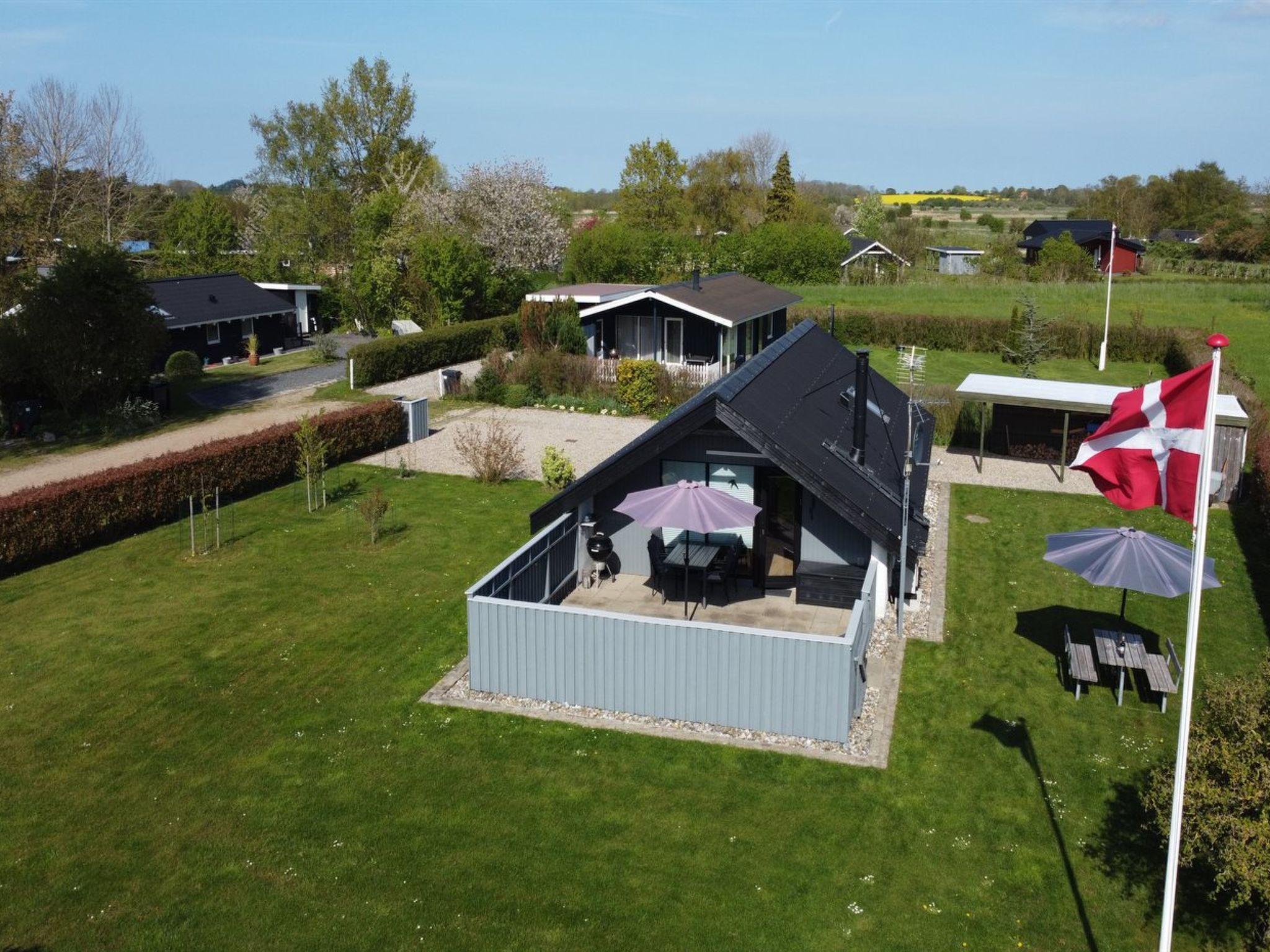 A modern house with a large deck, a barbecue area, and a flagpole with a flag.