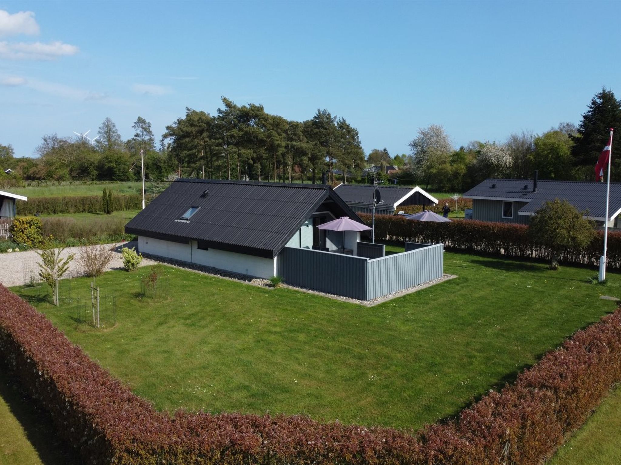 En boligbygning med skråt tag, indhegnet gård og flagstang.