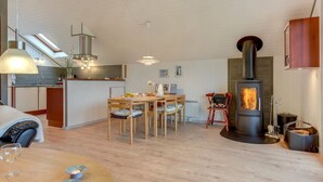 Une cuisine moderne dotée d’un îlot central, d’un coin repas avec des chaises en bois et d’un poêle à bois.