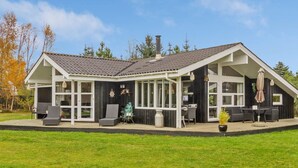 Een modern huis met een overdekte patio, grote ramen en een zitgedeelte buiten.