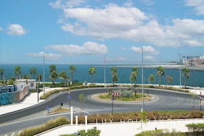 Una carretera costera con palmeras, una glorieta y vistas al mar.