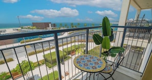 A balcony with a view of the sea, a pool, and a road.