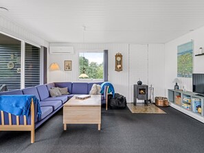 Een moderne woonkamer met een blauwe bank, een houten salontafel en een kleine open haard.