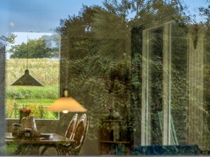 Een kamer met uitzicht op een grasveld, een hanglamp en een stoel.