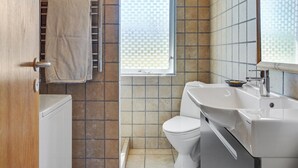 Une salle de bain avec des toilettes blanches, un lavabo et un porte-serviettes.