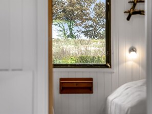 Een kamer met een raam dat uitkijkt op een grasveld en bomen.