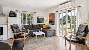 A modern living room with a sofa, chairs, a coffee table, and a kitchen area with a microwave.