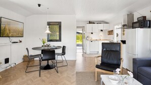 A modern living room with a dining area, a kitchen, and a view of the outdoors.