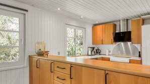 Een moderne keuken met houten kastjes, een roestvrijstalen afzuigkap en een ingebouwde oven.