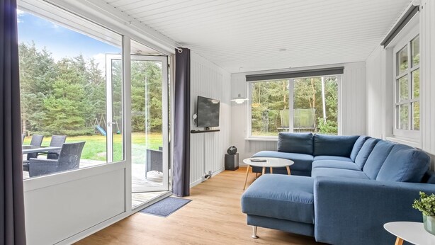 Een moderne woonkamer met een blauwe bank, een klein rond tafeltje en een aan de muur bevestigde televisie.
