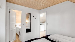 Un dormitorio con dos camas, techo de madera, un espejo y vistas a la cocina.