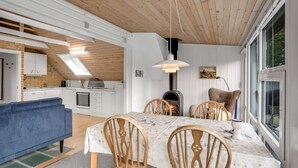 Una cocina moderna con armarios blancos, un sofá azul y una zona de comedor con sillas y una mesa de madera.