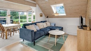 Un moderno apartamento tipo loft con un amplio sofá modular, un comedor y una pequeña mesa redonda.