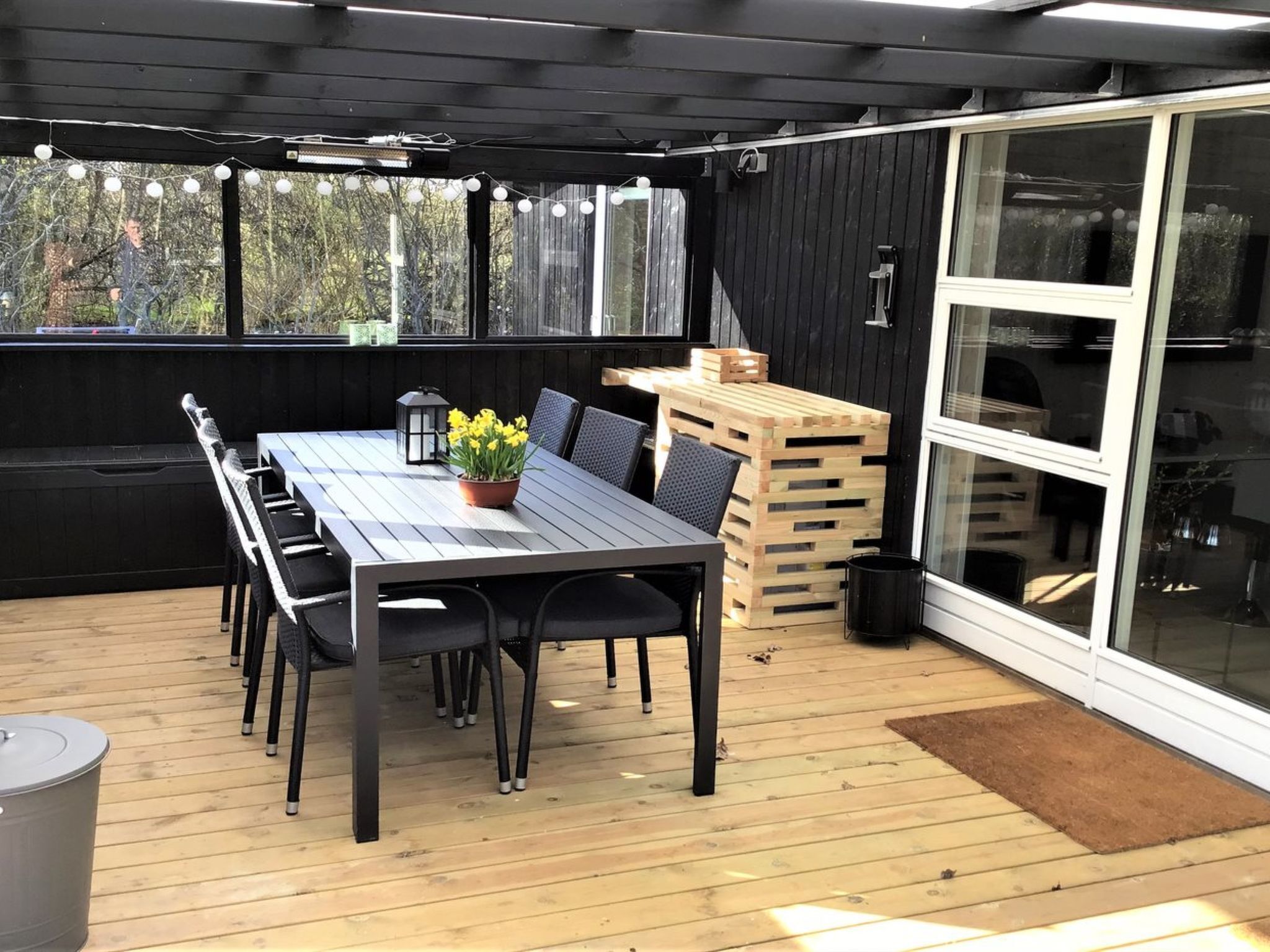 Une terrasse extérieure avec une table en bois, des chaises et une lanterne.