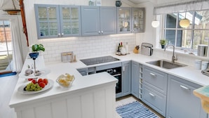 A modern kitchen with white and light blue cabinets, a central island with fruit, and a window with a view. - "Fido" - 300m from the sea by Interhome (Hals)