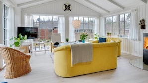 A spacious living room with a yellow sofa, a television, and a fireplace. - "Fido" - 300m from the sea by Interhome (Hals)