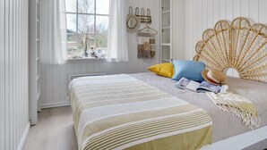 A bedroom with a bed, a window with curtains, a wall-mounted hat rack, and a wicker fan. - "Fido" - 300m from the sea by Interhome (Hals)