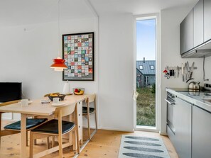 Una cucina moderna con zona pranzo, un'ampia finestra e vista su una casa.