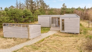 Un chalet moderne et minimaliste, avec un chemin de gravier menant à l’entrée.