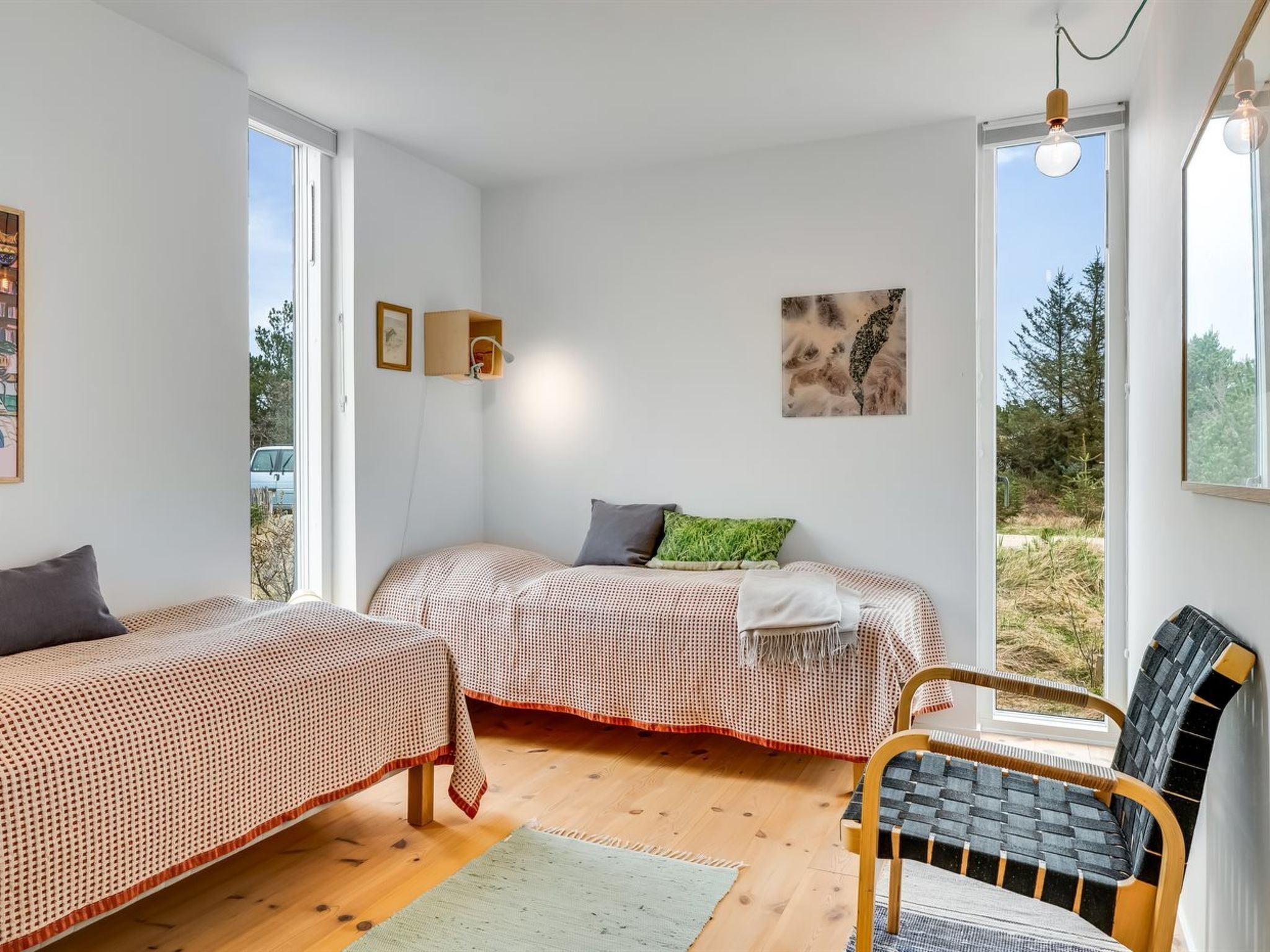 Una habitación con dos camas, una silla, una lámpara y un cuadro.