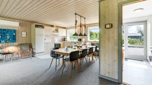 Una cucina moderna con mobili in legno, un'area pranzo con tavolo e sedie, e un'ampia finestra che offre luce naturale.