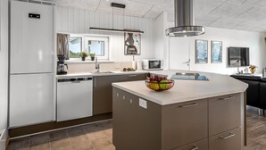 A modern kitchen with a central island, built-in appliances, and a large window.