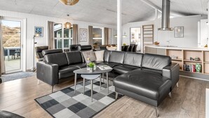 A modern living room with a sectional sofa, a round coffee table, and a hanging pendant light.