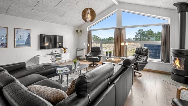 A modern living room with a sectional sofa, a fireplace, and a large window offering a view of the outdoors.