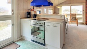 A compact kitchen with a built-in oven, a coffee maker, and a blue range hood.