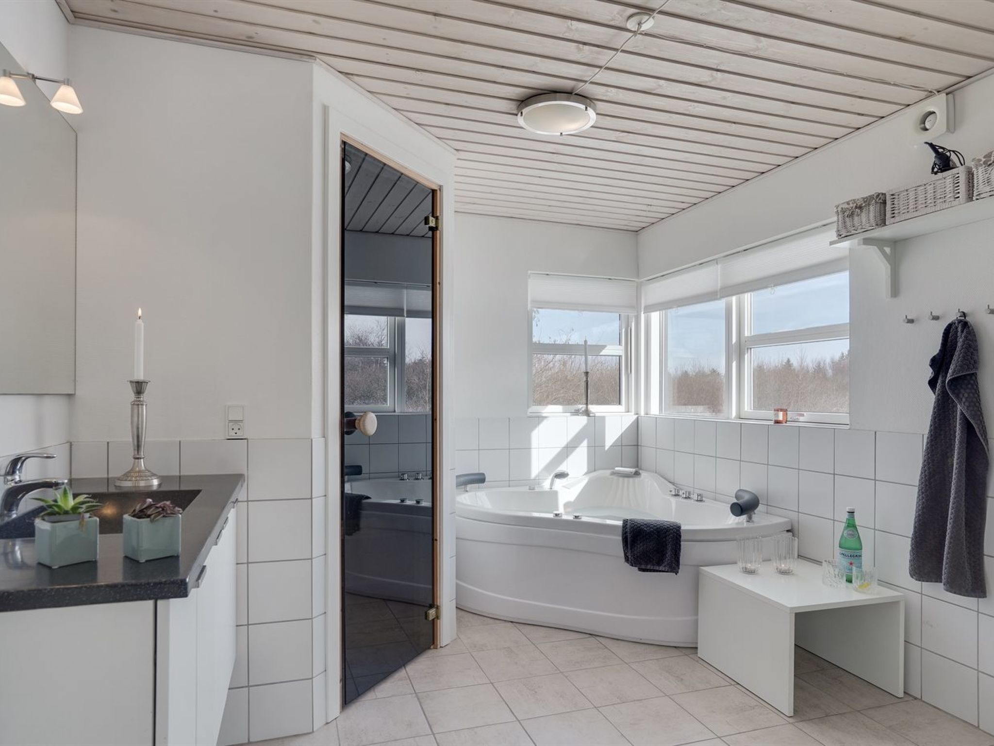 Ein modernes Badezimmer mit Badewanne, Waschtisch mit Spiegel und einem Fenster f ür natürliches Licht.