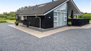 Ett modernt hus med ett stort garage, en täckt uteplats och en grusuppfart.