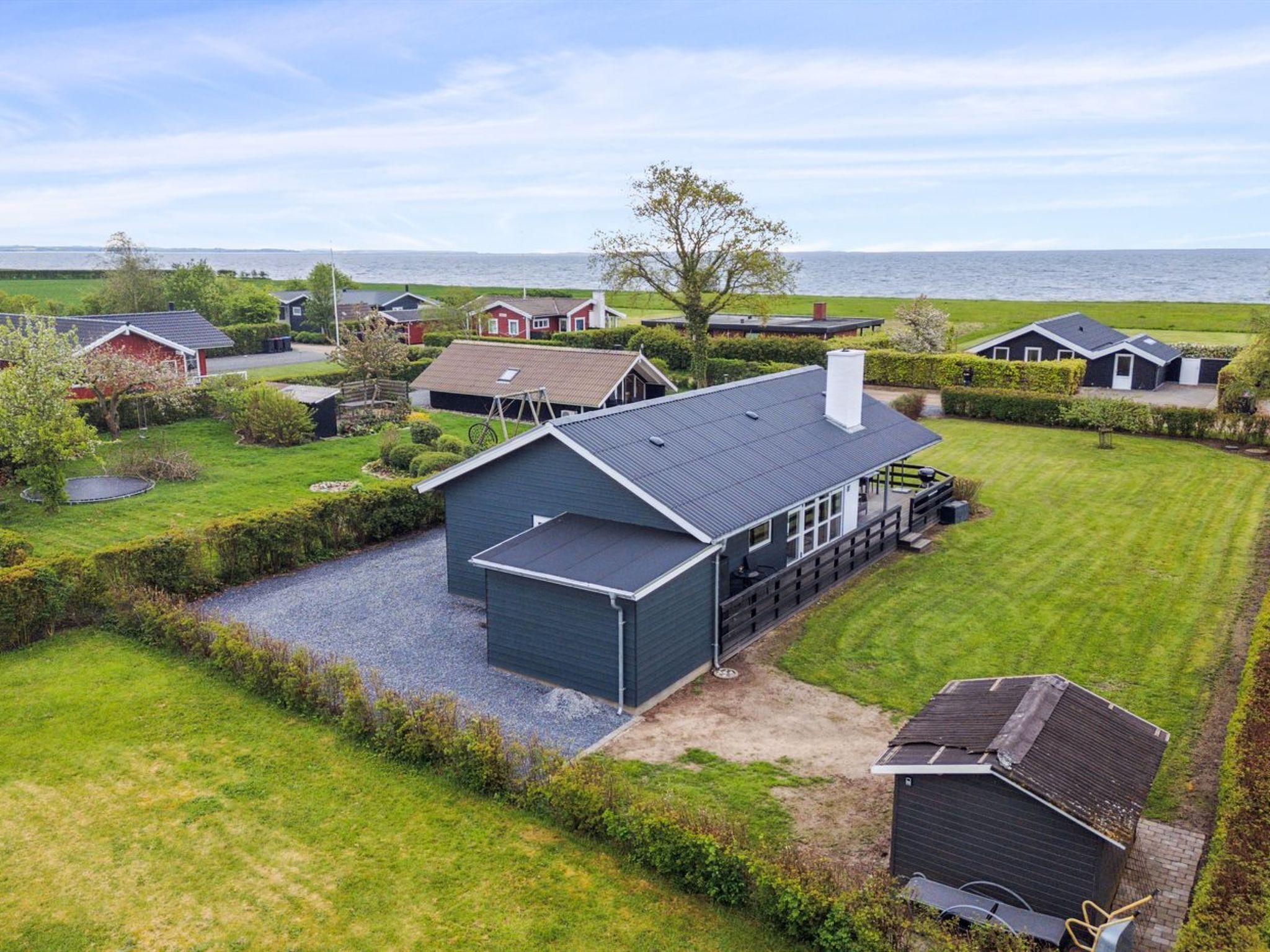 A residential area with houses, a large body of water in the background, and a well-maintained lawn.