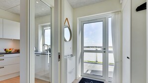 Een moderne keuken met witte kastjes, een fruitschaal en een raam met uitzicht op een balkon.