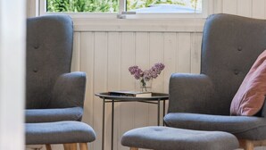 A room with two grey armchairs, a small table with a book and a vase of flowers, and a window with a view of greenery. - "Self" - 400m to the fjord by Interhome (Løgstrup)