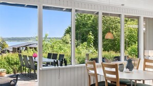 A covered patio with a view of a lake, outdoor seating, and a table with chairs. - "Self" - 400m to the fjord by Interhome (Løgstrup)