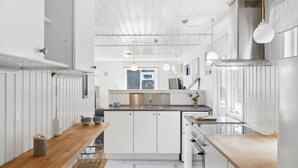 A modern kitchen with white cabinetry, a wooden countertop, and pendant lighting. - "Self" - 400m to the fjord by Interhome (Løgstrup)
