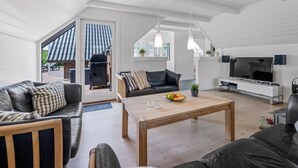 A spacious living area with a high ceiling, a fireplace, a TV, and a dining table with fruit. - "Lidija" - 850m from the sea by Interhome (Ringkøbing)