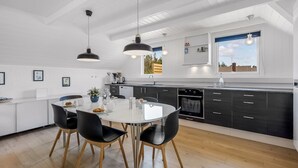 A modern kitchen with a central island, black chairs, and pendant lighting. - "Lidija" - 850m from the sea by Interhome (Ringkøbing)