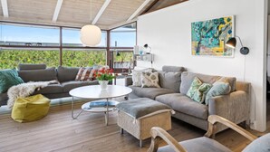 Ein modernes Wohnzimmer mit einer großen Couch, einem Couchtisch und Blick ins Grüne.