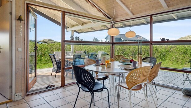 Ein moderner Essbereich mit großem Tisch und Stühlen, großen Fenstern und Blick ins Freie.