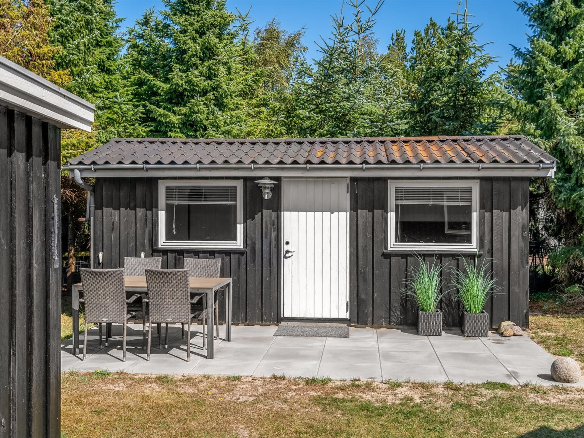 A wooden shed with a tiled roof, two windows, and a door.