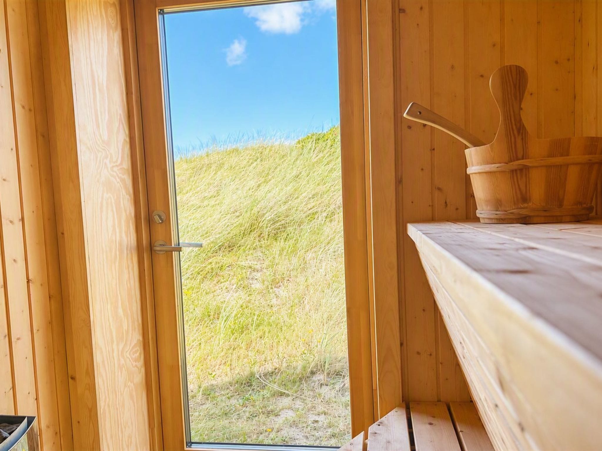 A wooden cabin with a door leading to a grassy outdoor area.