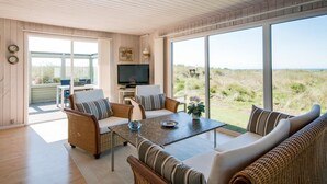 A spacious living room with a large TV, comfortable seating, and a view of the outdoors. - "Diuri" - 400m from the sea by Interhome (Saltum)