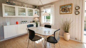 A dining area with a white table, black chairs, and a hanging light fixture. - "Diuri" - 400m from the sea by Interhome (Saltum)