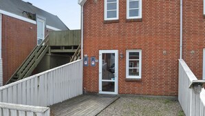 Un bâtiment en briques rouges avec une porte blanche et deux fenêtres.