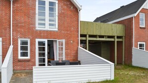 Une maison à deux étages, construite en briques, avec une façade blanche, un porche couvert et un garage.